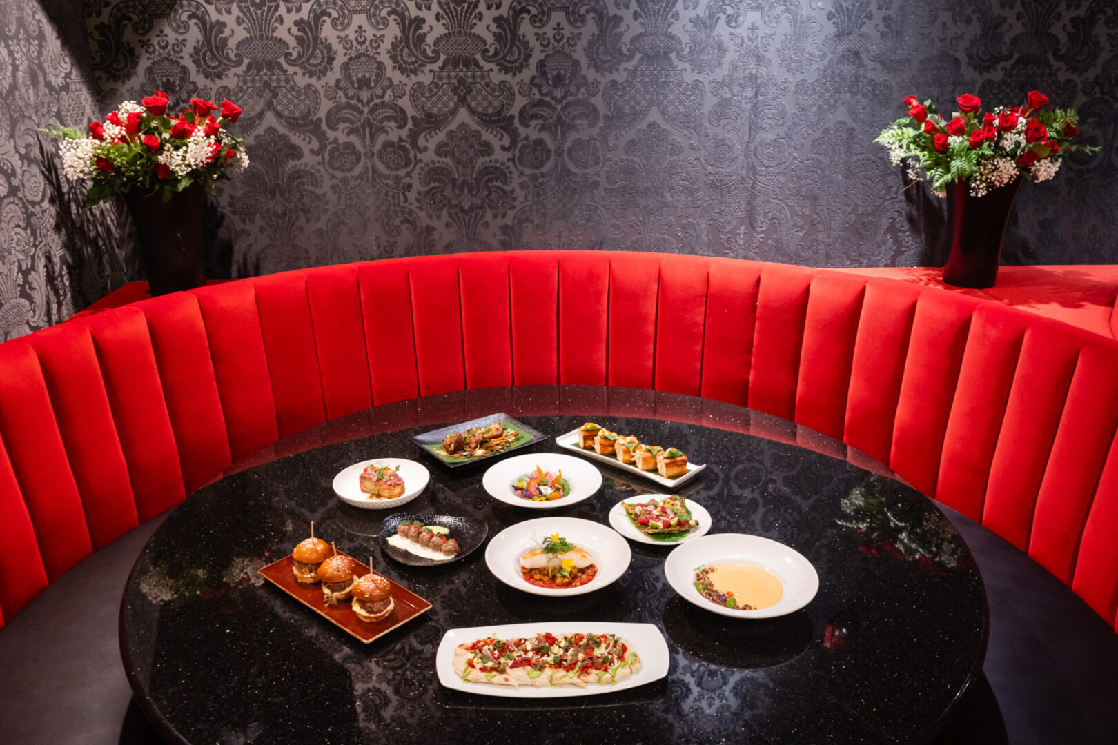 A round table in the luxury lounge with several plates of food on it.