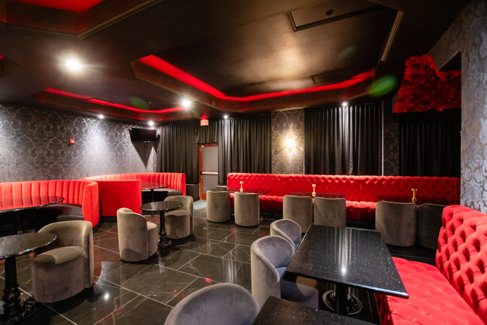A red and black luxury lounge with tables and chairs.
