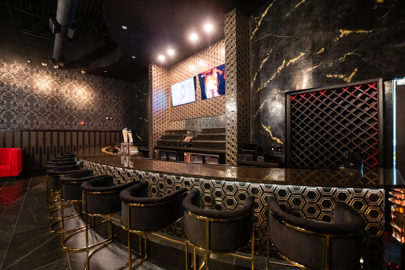 A luxury lounge with black and gold bar stools and a television.