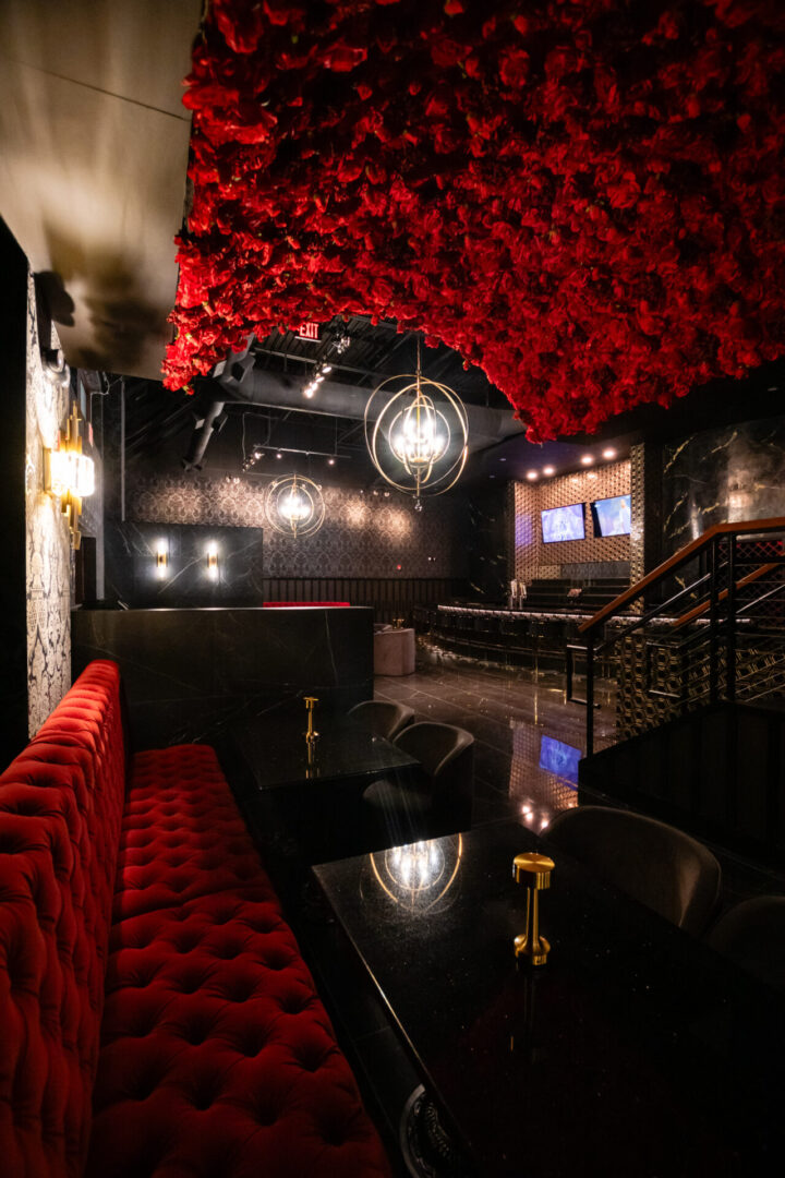 A luxury lounge with red couches and red roses hanging from the ceiling.