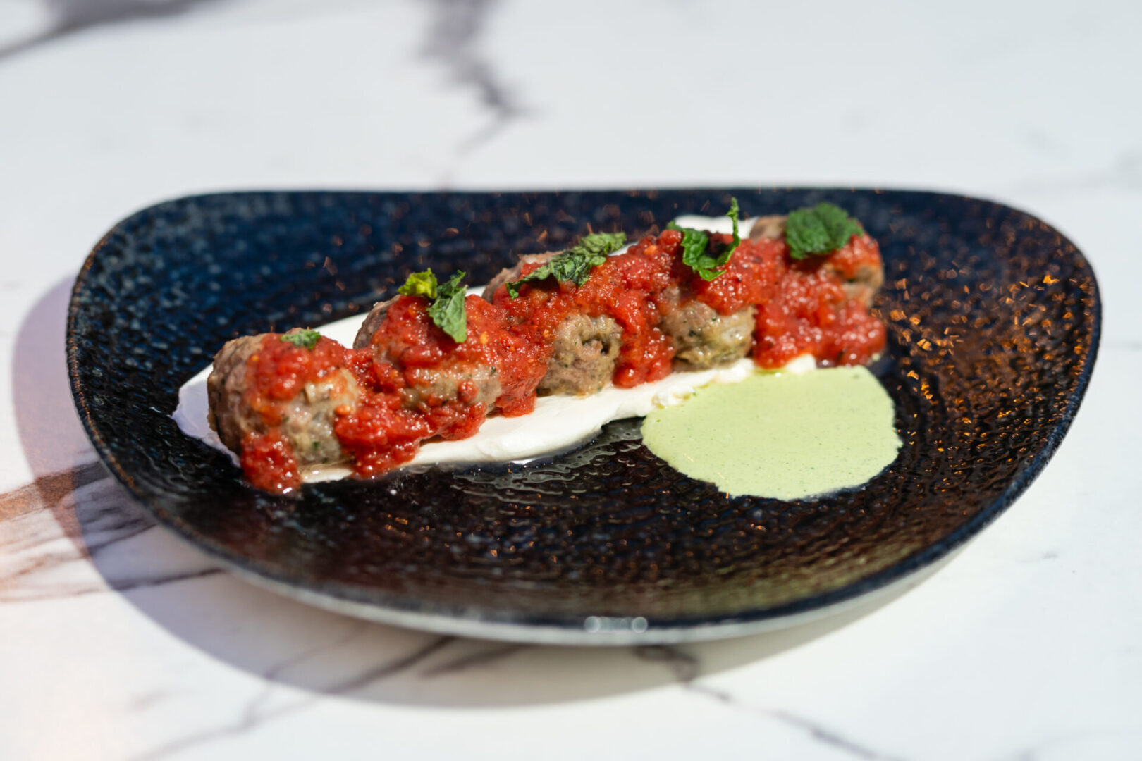 A plate with meatballs and sauce on it, served in a Luxury Lounge.