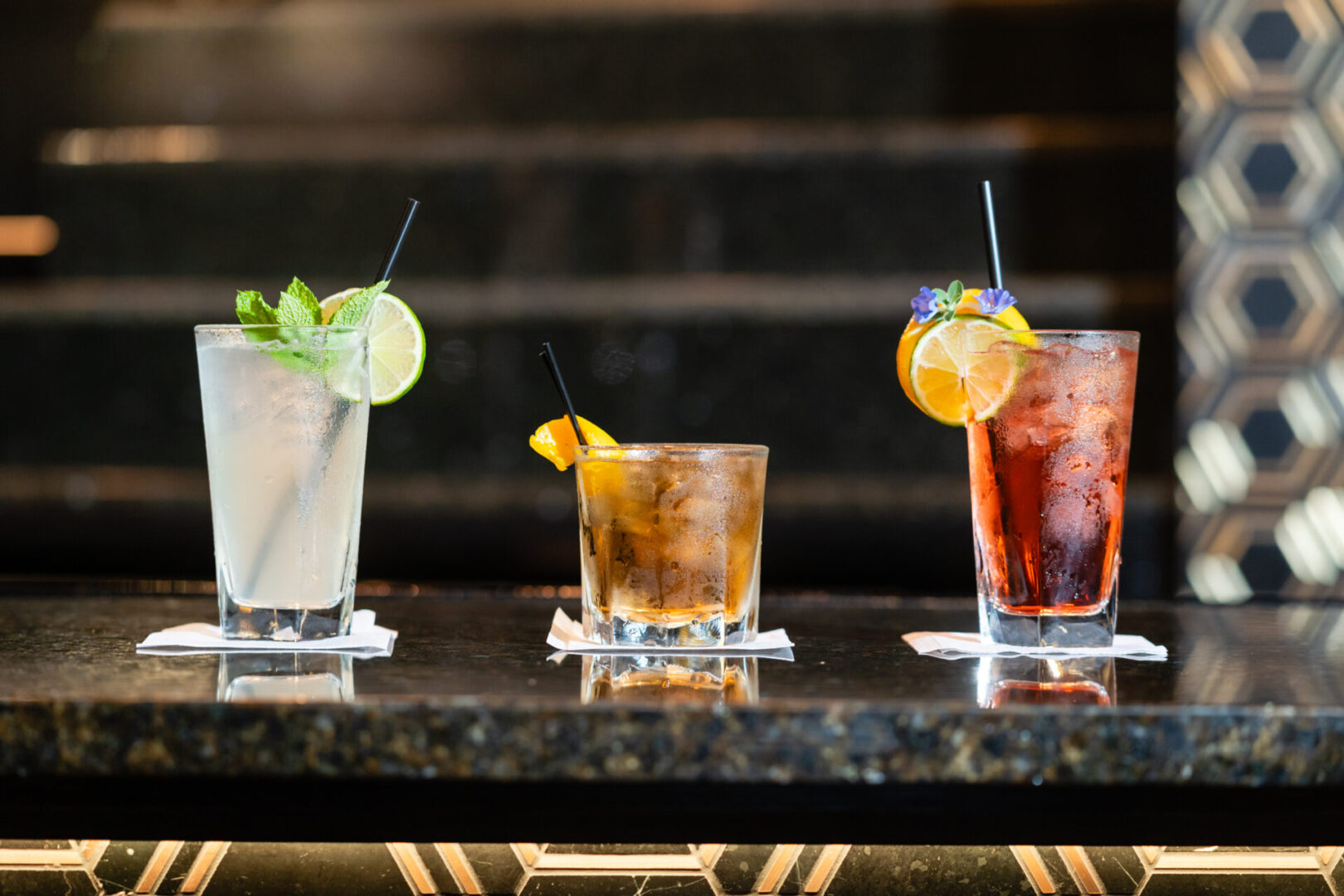 Four drinks are lined up on a luxury lounge bar.