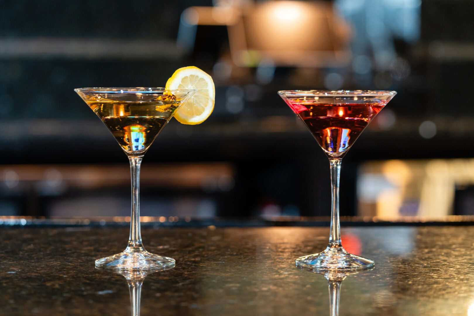 Two martinis on a bar with a lemon slice in a luxury lounge.