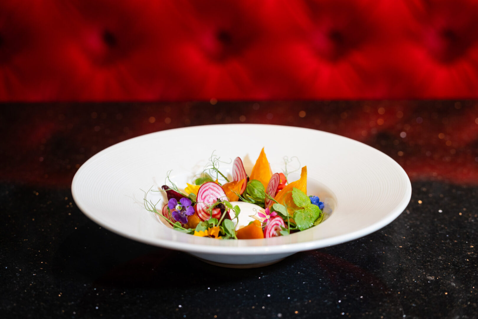 A white bowl with a salad in it, resting on a table in a luxury lounge.