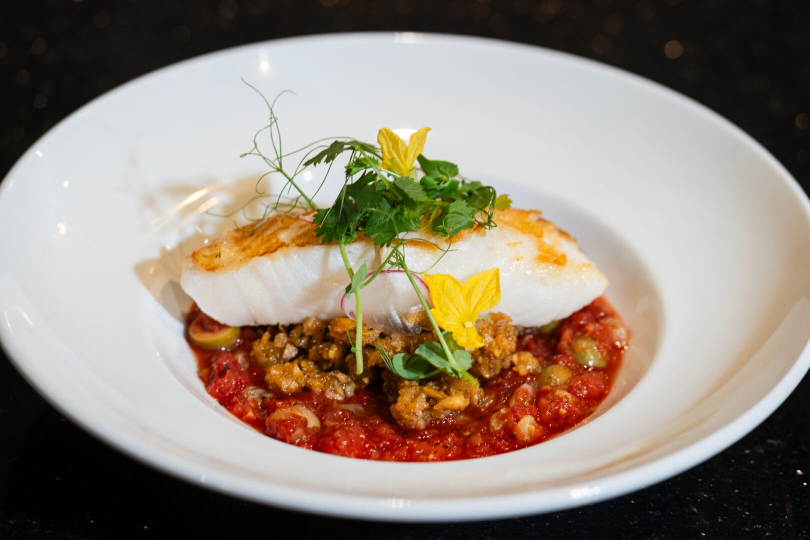 A luxury white plate with fish and vegetables on it.