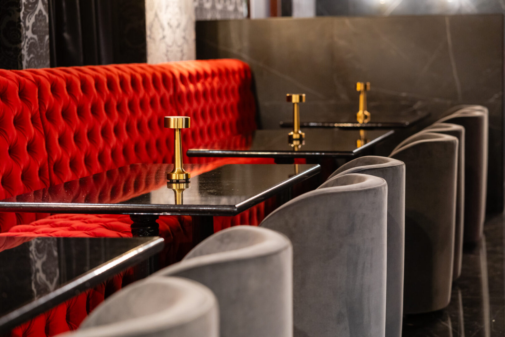 A row of luxury lounge tables with red velvet upholstered seats.
