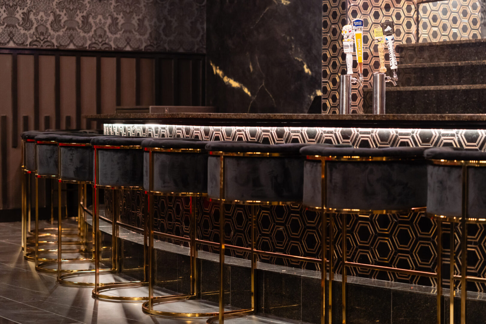 A black and gold luxury lounge with stools.
