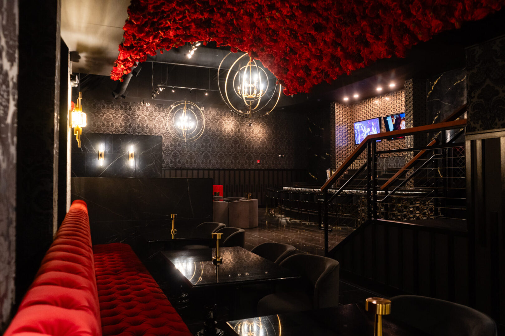 A luxury lounge with a black and red bar and a chandelier hanging from the ceiling.