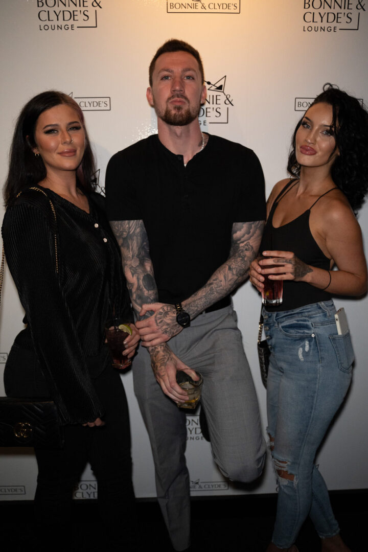 Three people posing for a photo at a luxury lounge event.